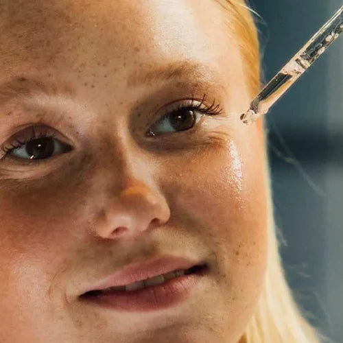 Young woman using product dropper to apply skin care