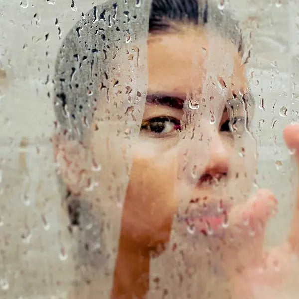 Woman in shower wiping the fog on the glass screen