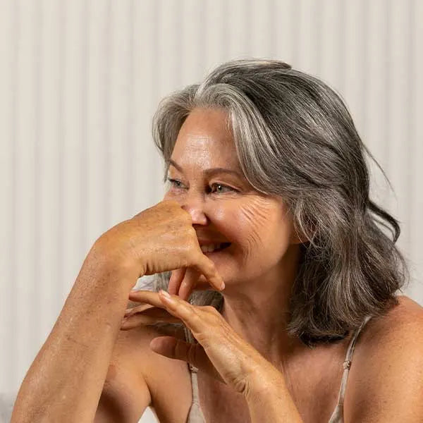 Middle aged woman smiling into her hands