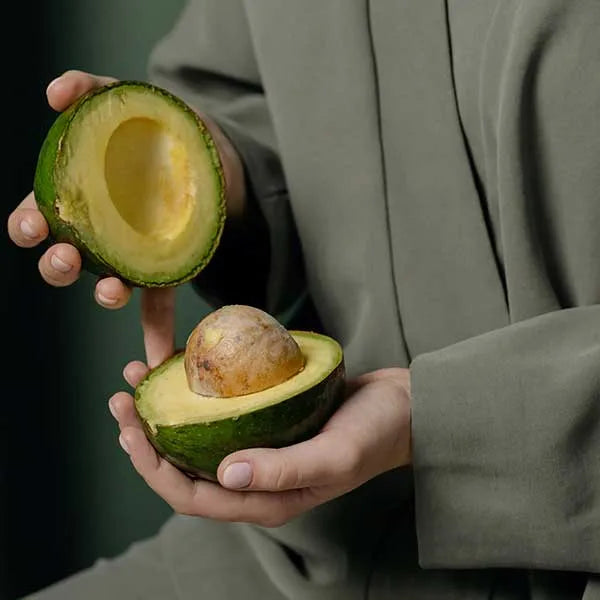 Man holding an avocado cut in half